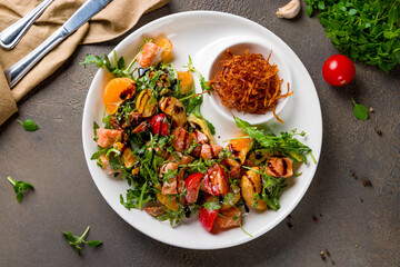 mixed salad with salmon and orange top view on white plate