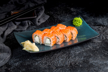 Philadelphia roll with salmon and cheese on plate on dark table