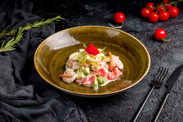 salad with shrimp, avocado and tomatoes on black table