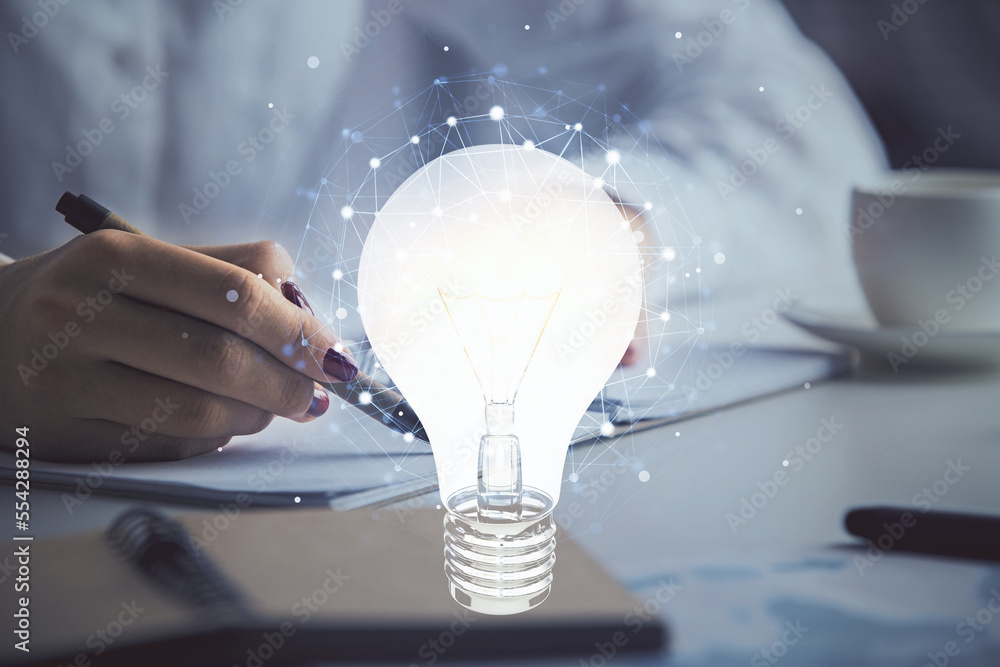 Poster bulb hologram over hands taking notes background. concept of idea. double exposure
