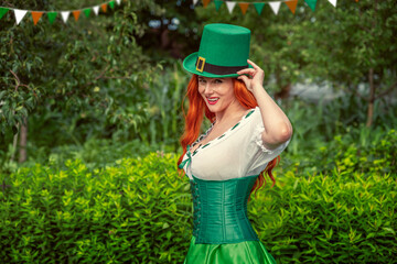 Happy Irish young red-haired woman in a green Leprechaun elf costume during a St. Patrick's Day...