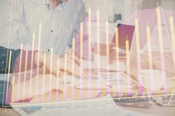 Multi exposure of chart with man typing on computer in office on background. Concept of hard work.