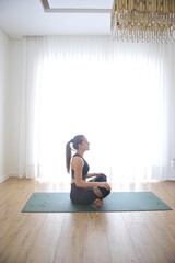 mulher linda fazendo alongamentos exercidios de yoga e meditação em casa 