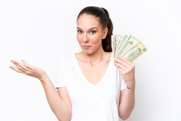 Young caucasian woman taking a lot of money isolated on white background having doubts while raising hands
