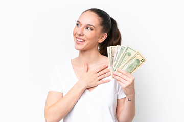 Young caucasian woman taking a lot of money isolated on white background looking up while smiling