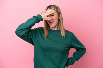 Young caucasian woman isolated on pink background covering eyes by hands and smiling