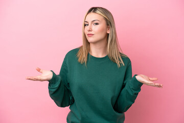 Young caucasian woman isolated on pink background having doubts