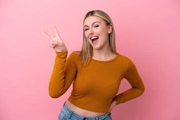 Obraz na płótnie Canvas Young caucasian woman isolated on pink background smiling and showing victory sign