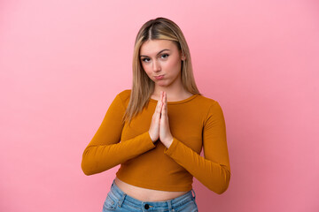 Young caucasian woman isolated on pink background keeps palm together. Person asks for something