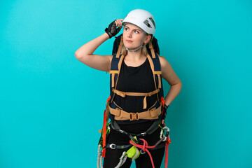 Young caucasian rock climber woman isolated on blue background having doubts and with confuse face expression
