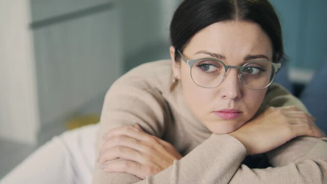 Depressed jobless woman sitting at home alone looking at window, procrastination