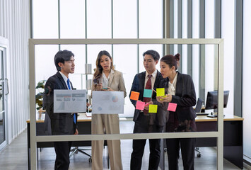 Employee meeting at office and use post it notes to share idea brainstorming stick on glass wall