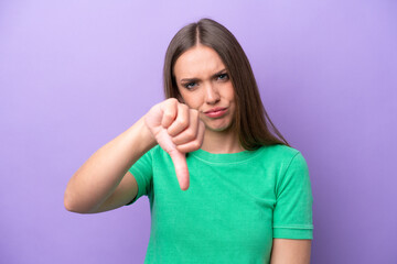 Young caucasian woman isolated on purple background showing thumb down with negative expression
