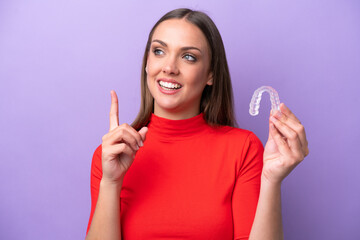Young caucasian woman holding invisible braces intending to realizes the solution while lifting a finger up