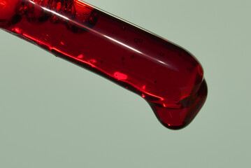Close-up of a micropipette with a red chemical liquid or blood for analysis under a microscope....
