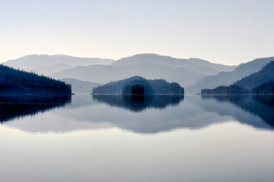 Clearing fog softly blankets islands and reflective waters of Sitka Sound, Alaska, USA