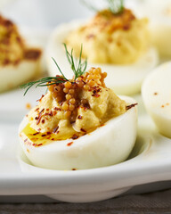 Deviled eggs garnished with paprika and dill on a white plate.