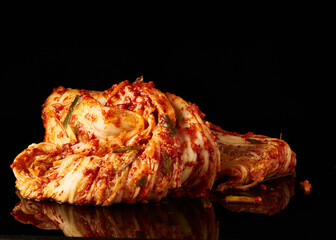 A vibrant pile of kimchi, with a glossy finish, set against a dark backdrop, perfect for a culinary...