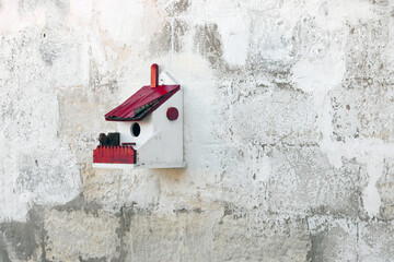 Hand crafted wooden bird house shelter for birds hanging on a white wall