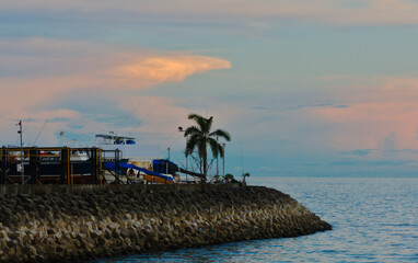 sunset in coastal zone, boats and breakwaters