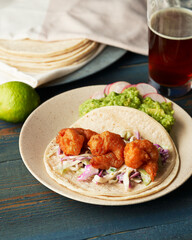 Fried Shrimp Taco with coleslaw guacamole and beer on rustic blue wood table