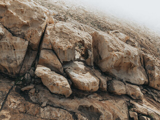 Photo taken with a drone of a person is sitting in a hole in the middle of a cliff