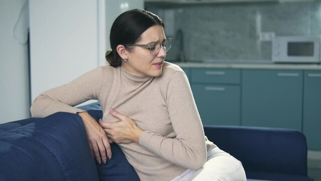 Unhappy brunette woman feeling pain in her breast, mammary gland inflammation