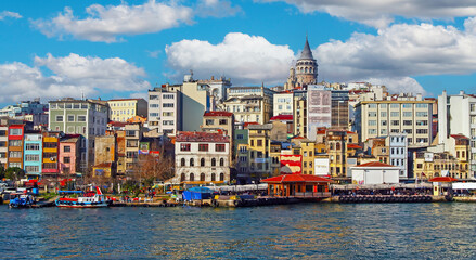 Obraz premium Istanbul, Turkey - February 24. 2017: Panorama city skyline view on historic peninsula Galata district (Karaköy), Sarayburnu tower across the bosphorus Golden Horn estuary waterway in springtime
