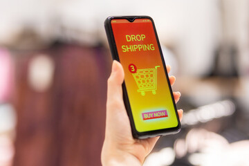 Close up of female hand holding smartphone with online store in screen. Purchase and drop shipping payed order. Concept of online shopping and consumerism