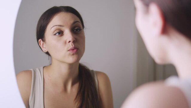 Beautiful healthy young woman looking at her reflection at mirror sending kiss