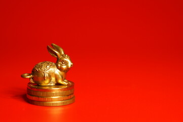 Fototapeta na wymiar Rabbit figurine with coins on a red background. Financial symbol. The year of the rabbit.
