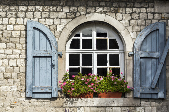 Close-up of wooden shutters on an arched window on a stone building with flower boxes; Namur, Belgium
