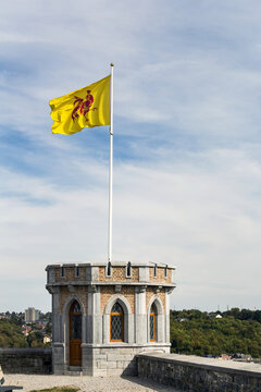 Close-up of castle turret with flag waving on pole with blue sky and clouds; Namur, Belgium