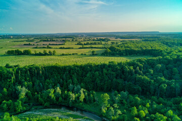 Obraz premium An aerial drone shot of Green Pastures a forest and a valley with a river running through it. Taken from the air over 16 Mile Creek in Oakville with a blue sky Horizon