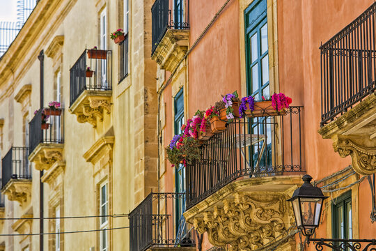 Facade of a residential building with balconies and blossoming plants; Syracuse, Sicily, Ortigia, Italy