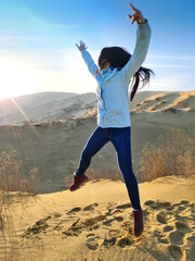 girl jumping on the sand dunes