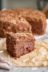 Napoleon cake with custard is decorated with cherries and grated chocolate on table.