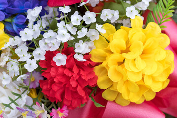 Close view of an assortment of vibrant artificial flowers with a pink ribbon.