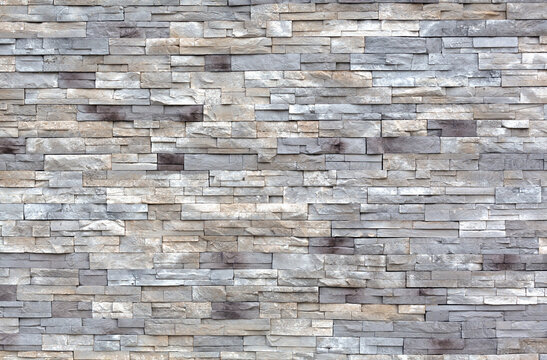 Rows of gray and white cut stone blocks for an exterior wall wide view.
