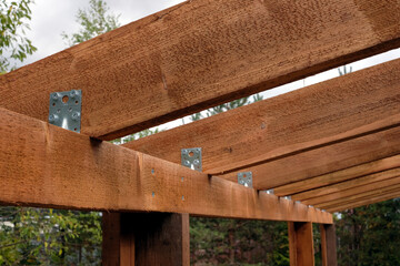 Board rafters and metal corners detail view in process of building a wooden canopy in the countryside place