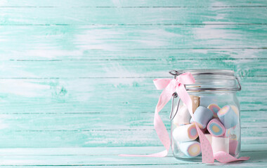 Glass jar full of colorful sweet marshmallows on turquoise wooden background. Place for text. St. Valentines day, Mothers day postcard. - 554314219