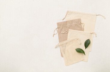 Small eco sacks with green leaves on light background. Top view