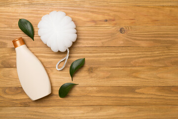 Shower gel with washcloth on wooden background, top view