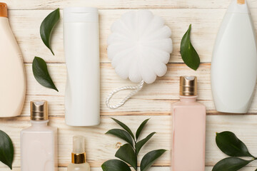 Different cosmetic bottles and washcloth on wooden background, top view
