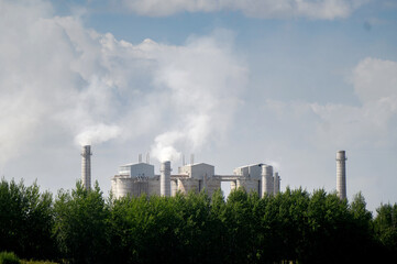 Fototapeta na wymiar Tall chimneys of a factory with smoke rising up, polluting the atmosphere. Air pollution concept.