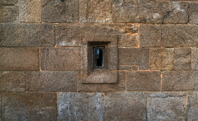 Fototapeta na wymiar Window in the stone wall of the old fortress