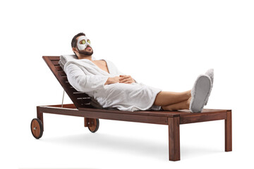 Man in a bathrobe with a face mask laying on a spa lounge chair