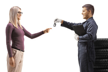 Auto mechanic with a pile of tires giving car keys to a woman