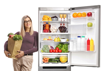Young woman with a grocery bag leaning on a fridge
