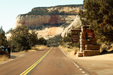 The main entrance sign into zion national park as you drive into the east entrance of the park. People stand infront of sign to get a photo before entering NPS. - obrazy, fototapety, plakaty